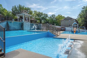 Ein Schwimmbad mit Wasserrutsche, einem Pavillon und einem Spielplatz.