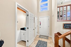 A hallway with a wooden door, a white door, and a window with a view of the sky. - Beach Bungalow: Soundside, Hot Tub, Sound Views, Village Beach Club Access (Nags Head)