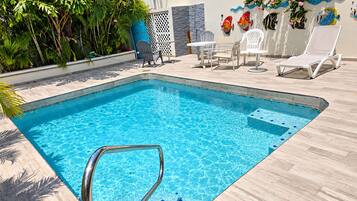 Une piscine rectangulaire avec un escalier en métal, entourée d’un revêtement de sol en carrelage de couleur claire.