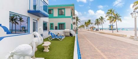 Un hotel frente a la playa con piscina, palmeras y cielo despejado.