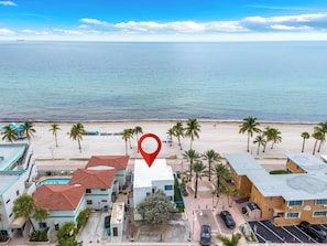 A coastal hotel with a view of the ocean, featuring a parking area, palm trees, and a red location marker. - Hollywood Beach | 3BR Steps to the Sand (Hollywood)