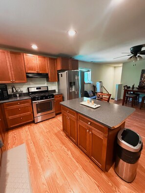 A kitchen with wooden cabinets, stainless steel appliances, and a granite countertop. - Cross Creek Cabin - Private Redwoods, 2 Creeks, Massage Bed & 100" Theater (Redway)