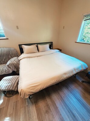 Ein Einzelbett mit Holzrahmen und einer weißen Matratze in einem Zimmer mit Holzboden.