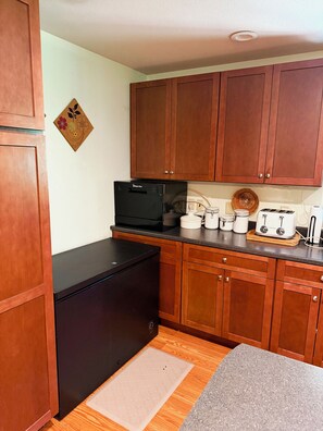 A compact kitchen with wooden cabinets, a black refrigerator, a microwave, a toaster, and a coffee maker. - Cross Creek Cabin - Private Redwoods, 2 Creeks, Massage Bed & 100" Theater (Redway)