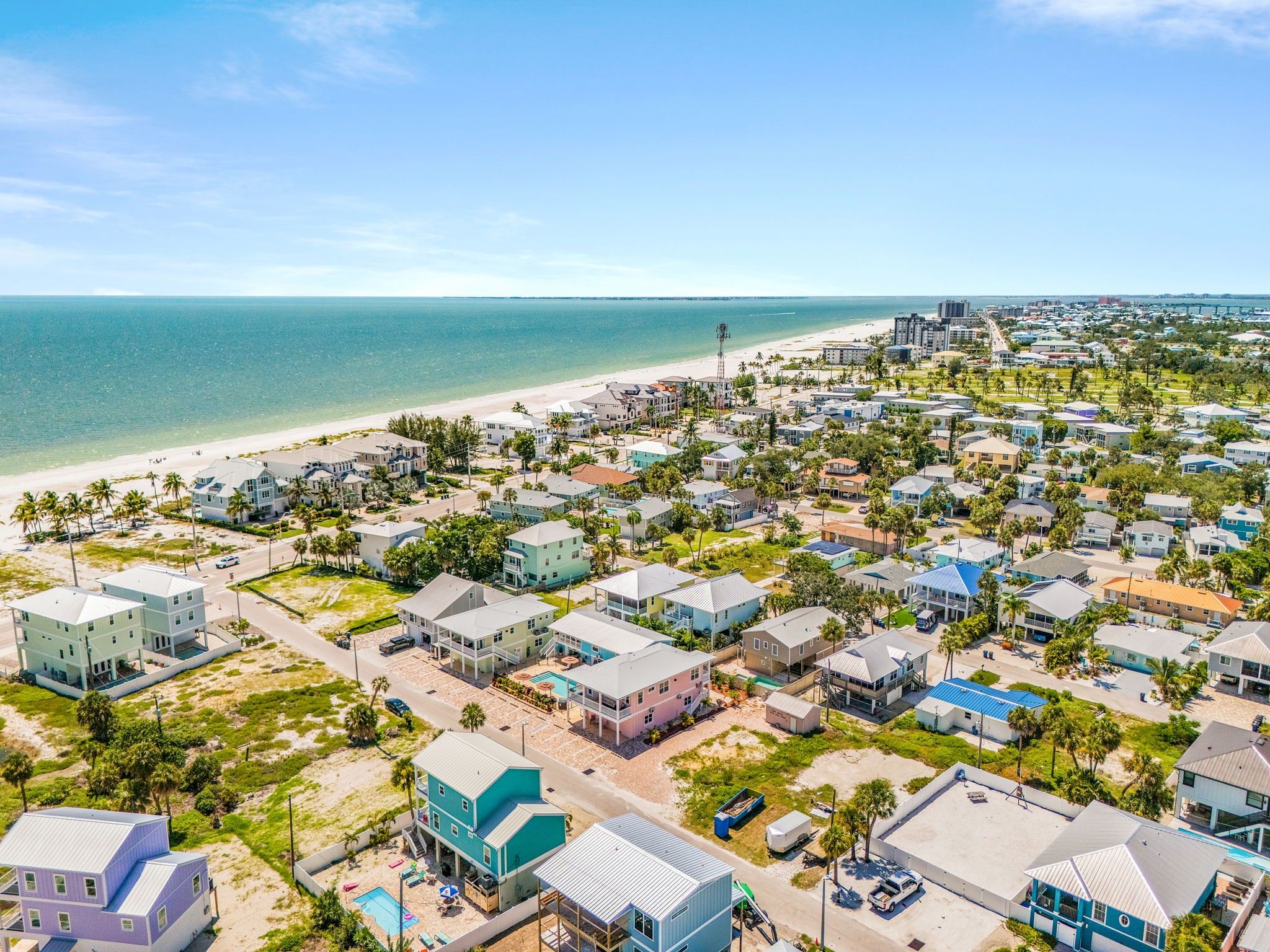 A coastal residential area with houses, a beach, and a clear view of the ocean.