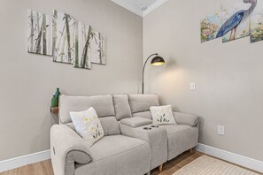A living room with a grey sectional sofa, two pillows, a floor lamp, and wall art. - Poolside Fun, Pickleball & Coastal Adventures Await in Fort Myers - Jefferson Palms II - Roelens (Fort Myers Beach)