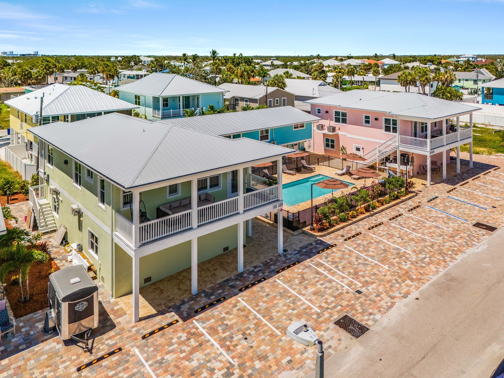 A coastal residential area with multiple two-story houses featuring balconies, a swimming pool, and a parking lot.