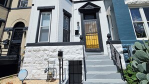 A two-story house with a stone facade, a black front door, and a small porch with steps.