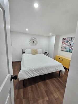 A bedroom with a bed, a wall-mounted decorative item, a bedside table, and a yellow cabinet.