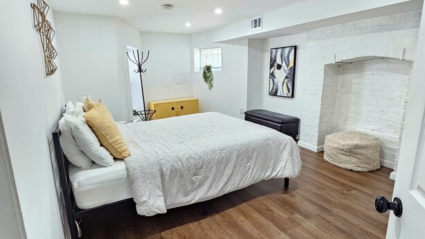 A bedroom with a bed, a bench, a fireplace, and a coat rack.