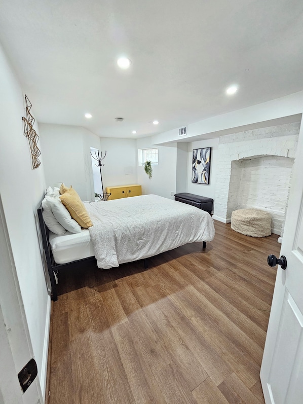 Un dormitorio con cama, una banca, chimenea y perchero.