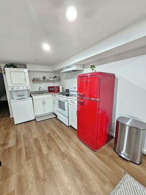A modern kitchen with white cabinetry, a red Galanz refrigerator, and a stainless steel trash bin.