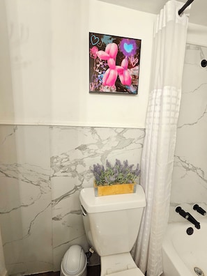 A bathroom with a toilet, a shower curtain, and a framed picture on the wall.