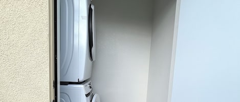A laundry room with a washing machine and dryer, a door leading to the outside, and a tiled floor.