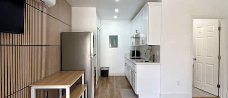 A modern kitchen with white cabinets, a microwave, and a built-in oven.