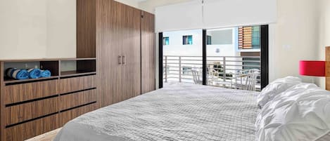 Une chambre à coucher comprenant un lit, une armoire et un balcon aménagé avec du mobilier d’extérieur.