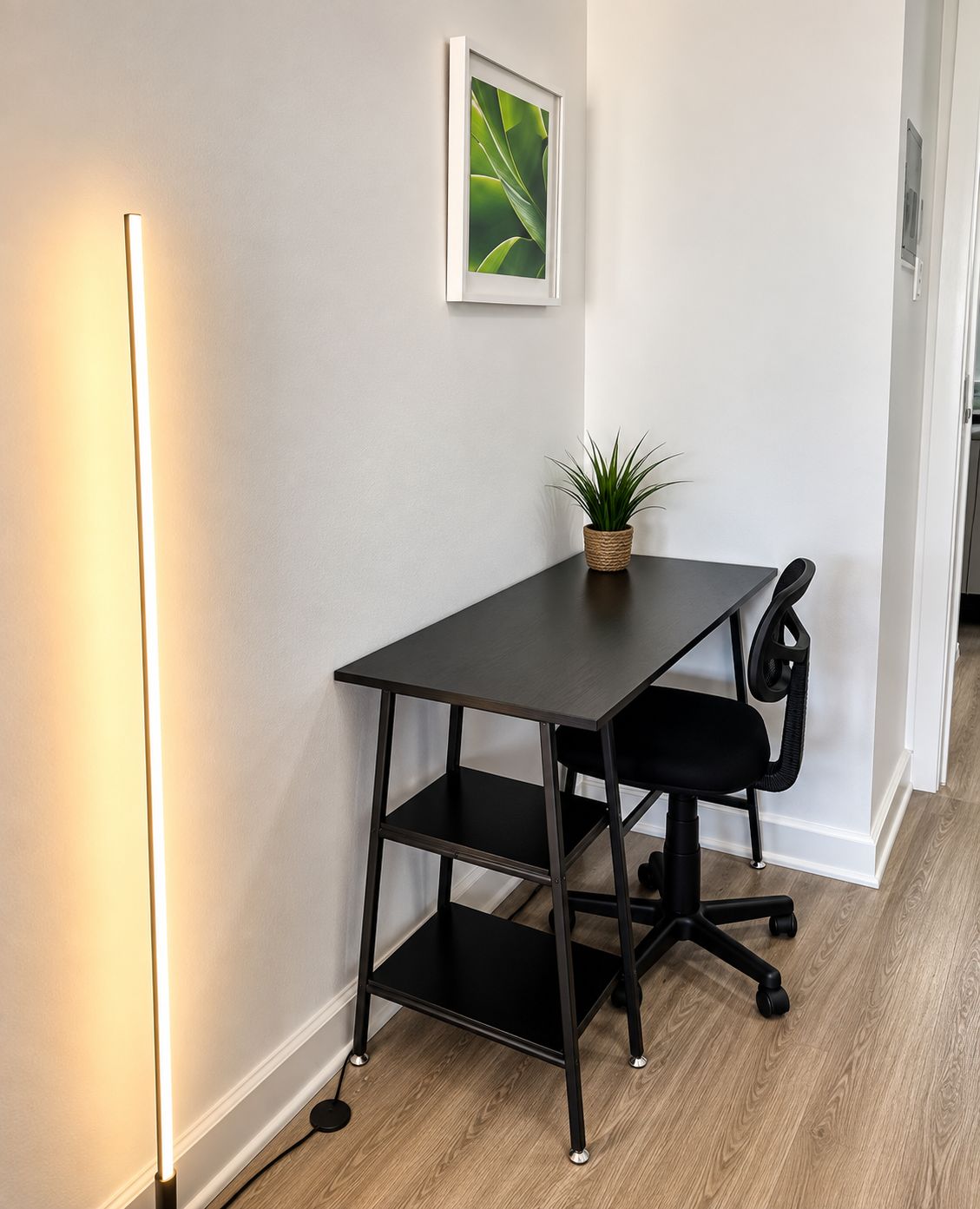 Un bureau moderne, avec une chaise, une plante en pot et un tableau encadré accroché au mur.