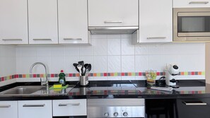 A modern kitchen with white cabinets, a stainless steel stove, and a microwave. - Mareverde Sea View Apartment with Pool (Costa Adeje)