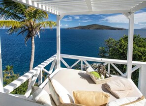 A white outdoor seating area with a view of the sea and a distant island. - Romantic Getaway | Oceanfront | Private Pool (St. Thomas)