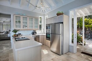 A modern kitchen with a central island, built-in oven, and a large refrigerator. - Romantic Getaway | Oceanfront | Private Pool (St. Thomas)