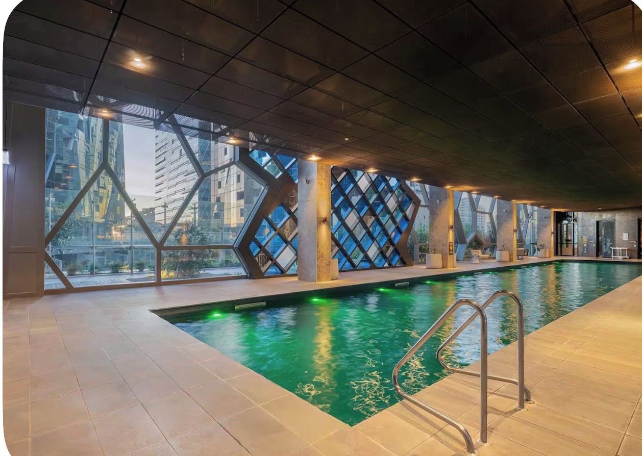 An indoor swimming pool with geometric glass walls and a modern design.