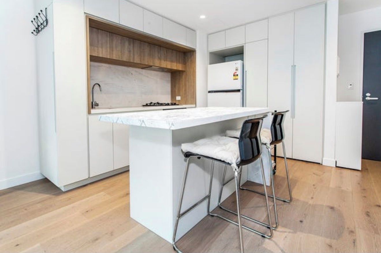 A modern kitchen with a central island, bar stools, and a built-in oven.