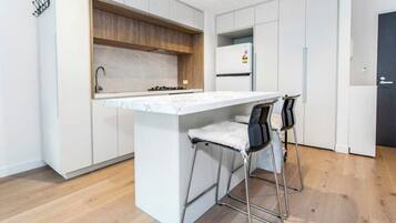 A modern kitchen with a central island, bar stools, and a built-in oven.