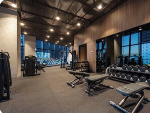 A gym with various exercise equipment, large windows, and a high ceiling. - Modern CBD Retreat | Pool, Sauna, Gym, BBQ  & City Views (Melbourne)