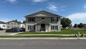 A two-story residential building with a front porch, a garage, and a driveway. - The Travelers Nest | BYUI, Island Park, & Targhee (Rexburg)