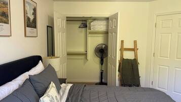 Een slaapkamer met een bed, een ventilator, een houten trap en een kast met kledingroede.