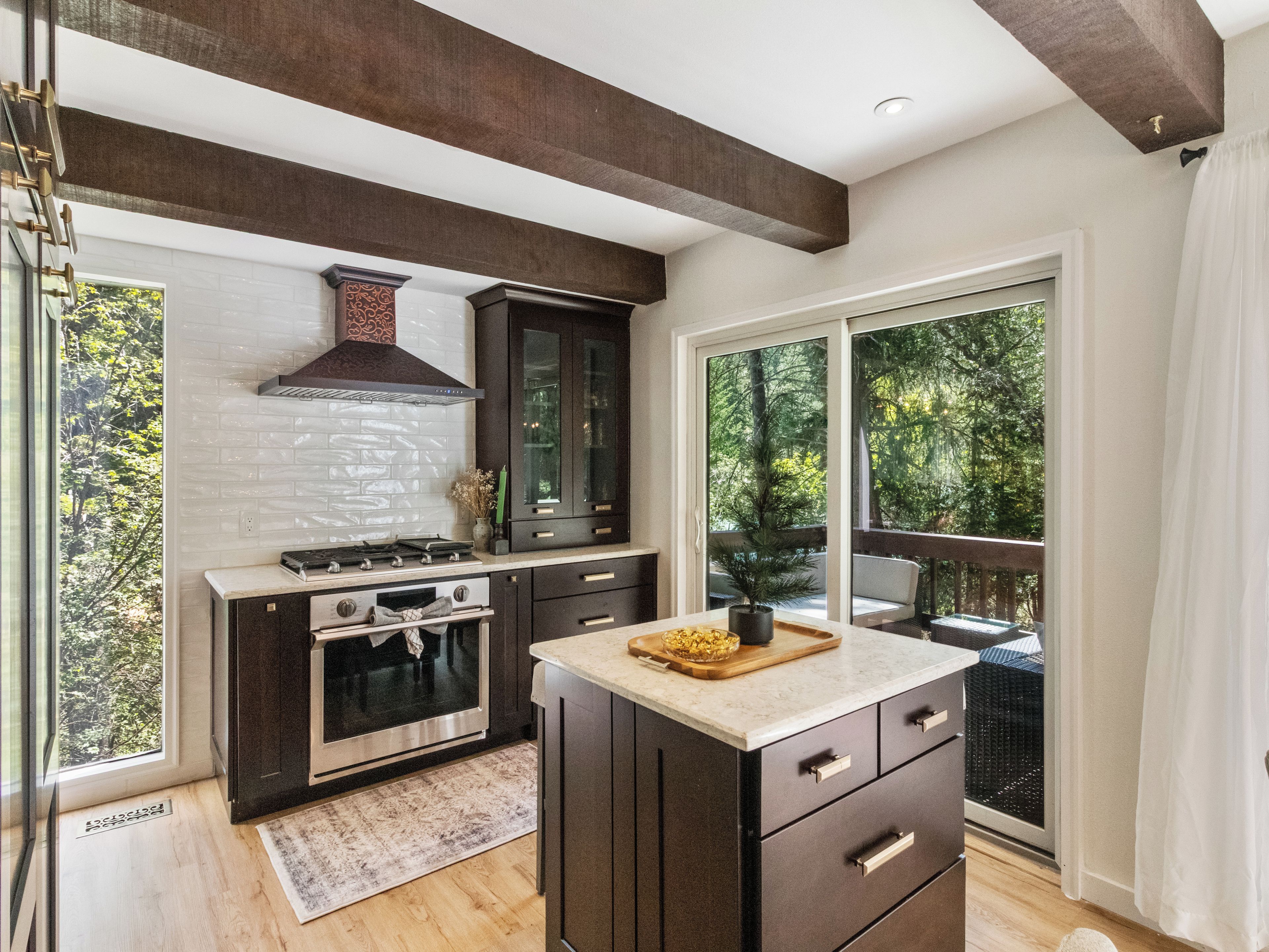 A modern kitchen with a central island, built-in appliances, and a large window offering a view of the outdoors.