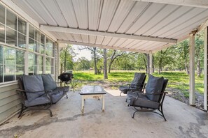 A covered patio with two chairs and a table, overlooking a grassy area with trees. - White Oak Retreat! 17 mins to Silos! (Waco)
