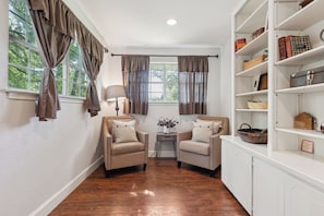 A room with two armchairs, a small table, a lamp, and a bookshelf with various items. - White Oak Retreat! 17 mins to Silos! (Waco)