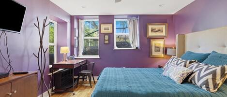 A bedroom with a bed, desk, chair, and a ceiling fan.