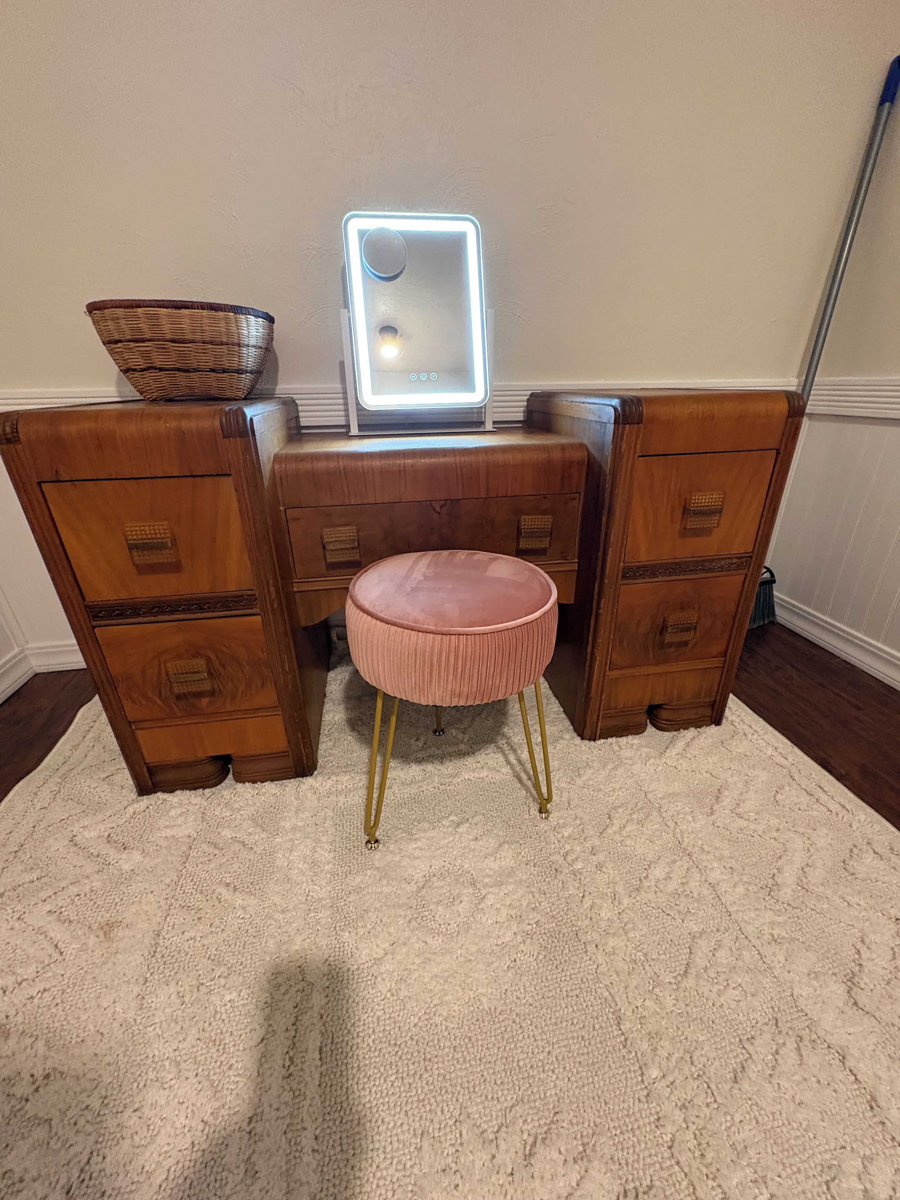 A vanity with a mirror, drawers, and a stool.