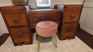 A vanity with a mirror, drawers, and a stool.