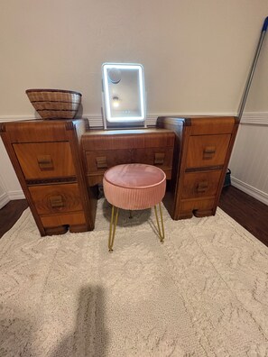 Une coiffeuse avec un miroir, des tiroirs et un tabouret.