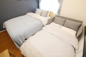 A double bed with white and light blue bedding, a grey headboard, and a window with curtains. - Lamarie Haneda 402 (Ota Ku)