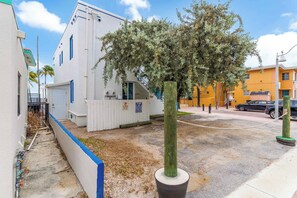 Ein Gebäude mit weißer Fassade, einem eingezäunten Bereich und einem Baum davor.