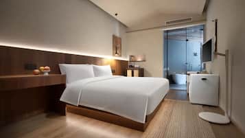 Una habitación de hotel moderna con una cama grande, una mesita de noche y un pequeño escritorio con una silla.