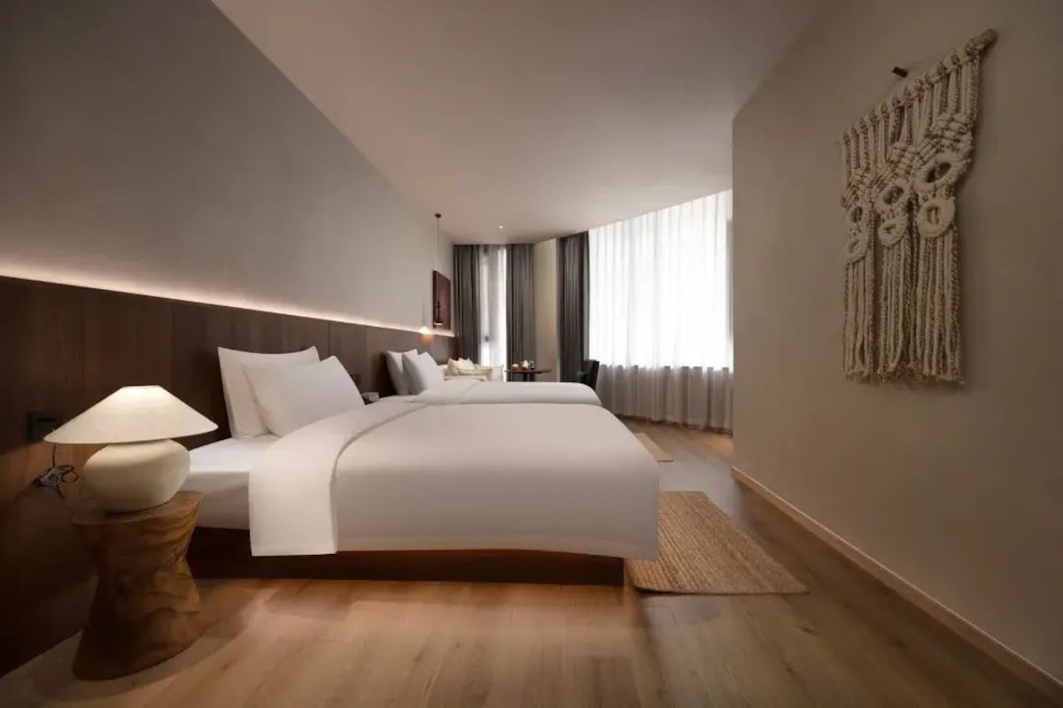 Quarto moderno com uma cama grande, mesas de cabeceira e um painel de macramé na parede.