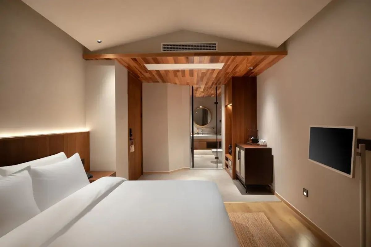 Quarto de hotel moderno com uma cama grande, televisão, escrivaninha e closet espaçoso.