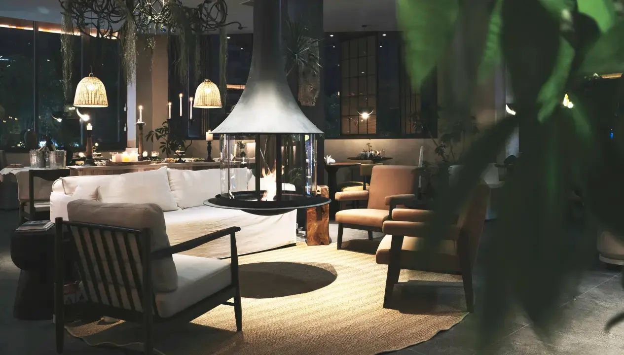 A modern living room with a sofa, armchairs, a coffee table, and a fireplace.