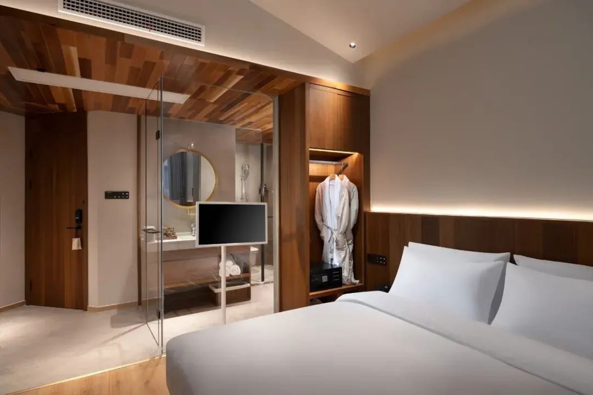 Quarto de hotel moderno com cama grande, closet espaçoso, televisão e espelho.