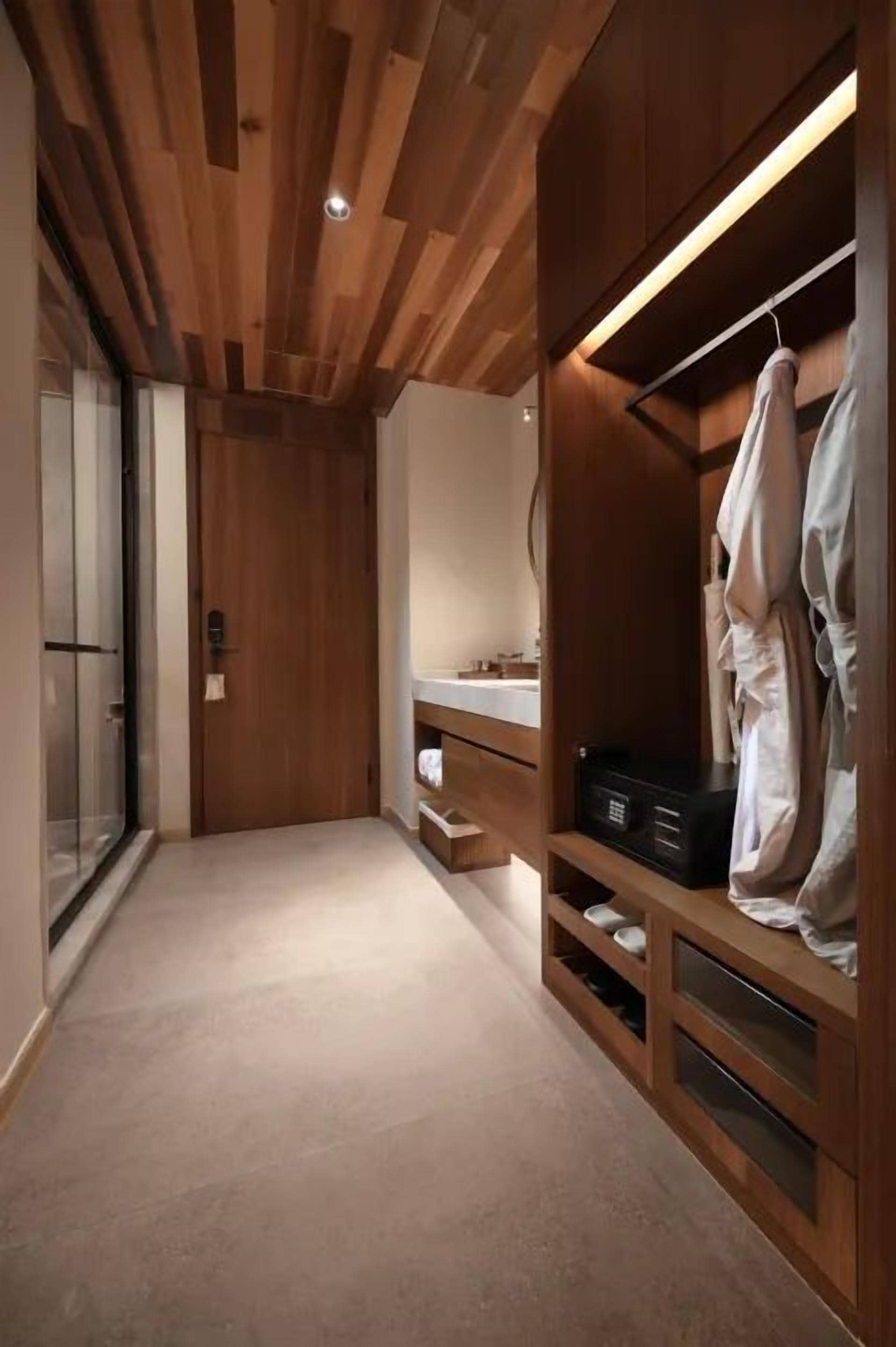Um closet amplo com prateleiras de madeira, cabideiro e espelho.