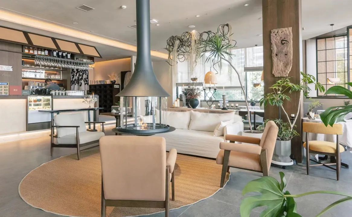 Un interior moderno con una zona de bar, asientos y una chimenea central.