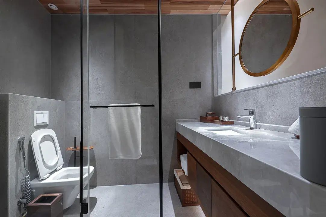 Een moderne badkamer met een douchecabine van glas, een toilet, een wastafel met een badmeubel en een spiegel.
