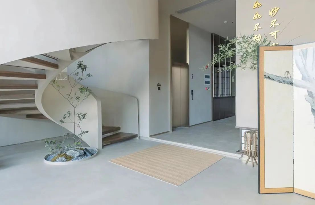 A modern interior with a curved staircase, a small indoor plant, and a framed artwork on the wall.