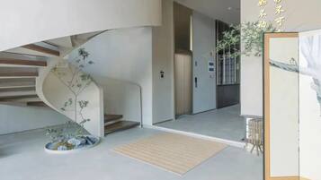 A modern interior with a curved staircase, a small indoor plant, and a framed artwork on the wall.