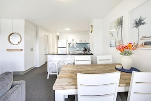 Een moderne keuken met witte kasten, een houten eettafel en een bloemenvaas.